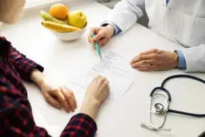 "A caring home health nurse reviewing insurance paperwork with an elderly patient and family member at home"